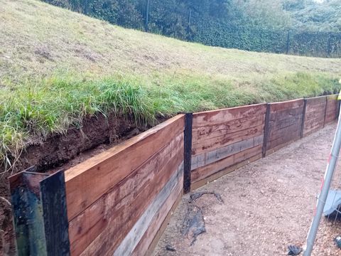 New timber retaining wall at the base of a grassed bank
