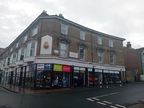 Three storey brick building with shops on a street corner in Cowes